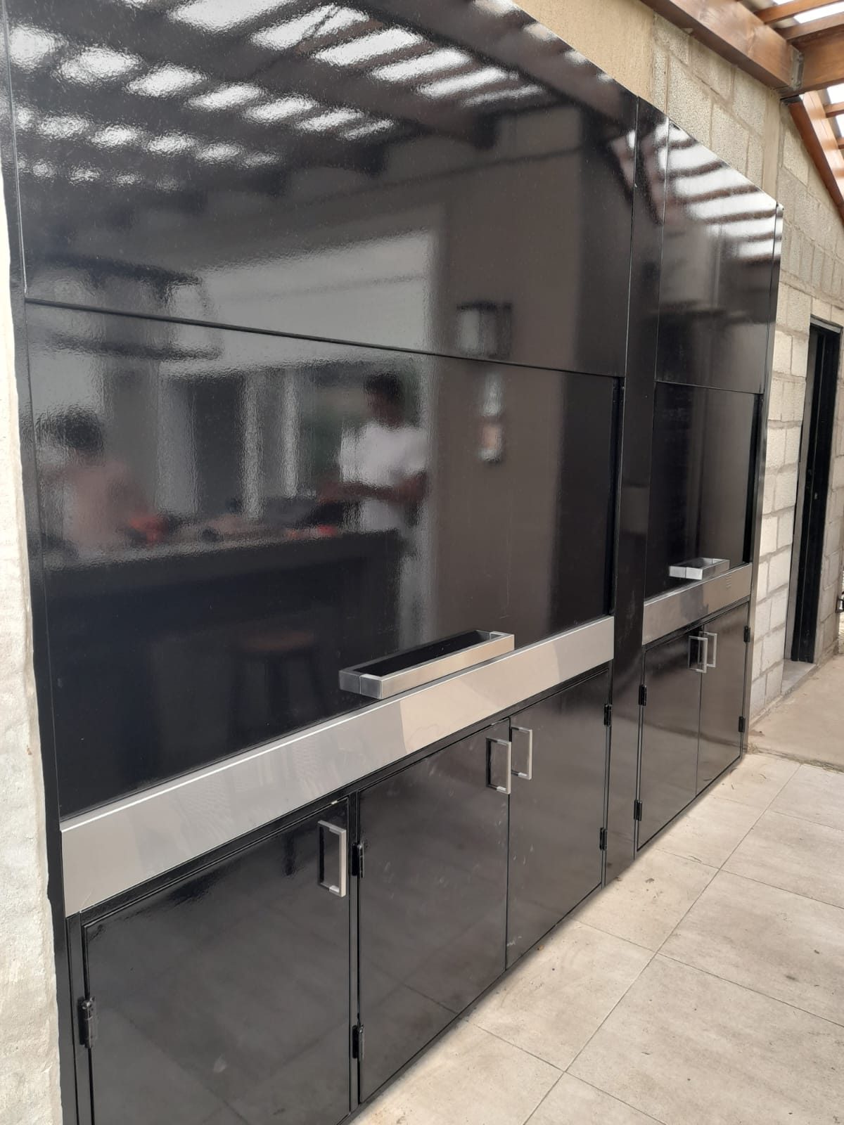 Frente de parrilla negro con puertas metálicas y mesada de acero