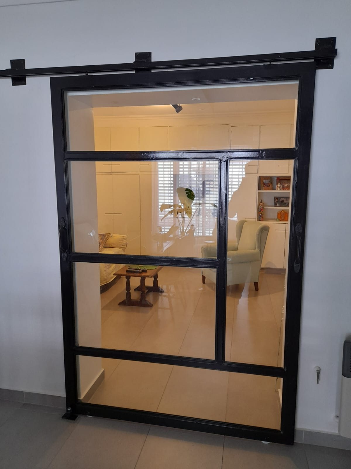 Puerta corrediza de hierro negro y paños de vidrio instalada en un interior
