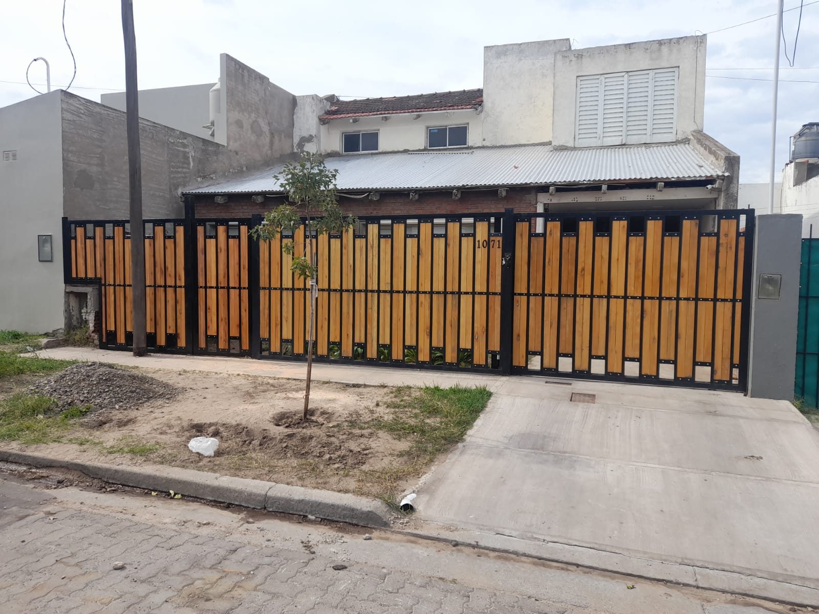 Portón corredizo de estructura negra con listones verticales de madera